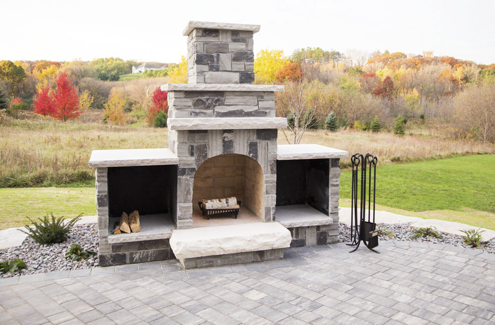 A natural stone fireplace is the focal point of this paver patio.