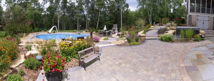 This stunning landscape has it all - a pool, fireplace, paver patio and walkways, outcroppings, and plantings.
