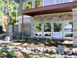 The landscape features a rain barrel system, fire table, and green roof.